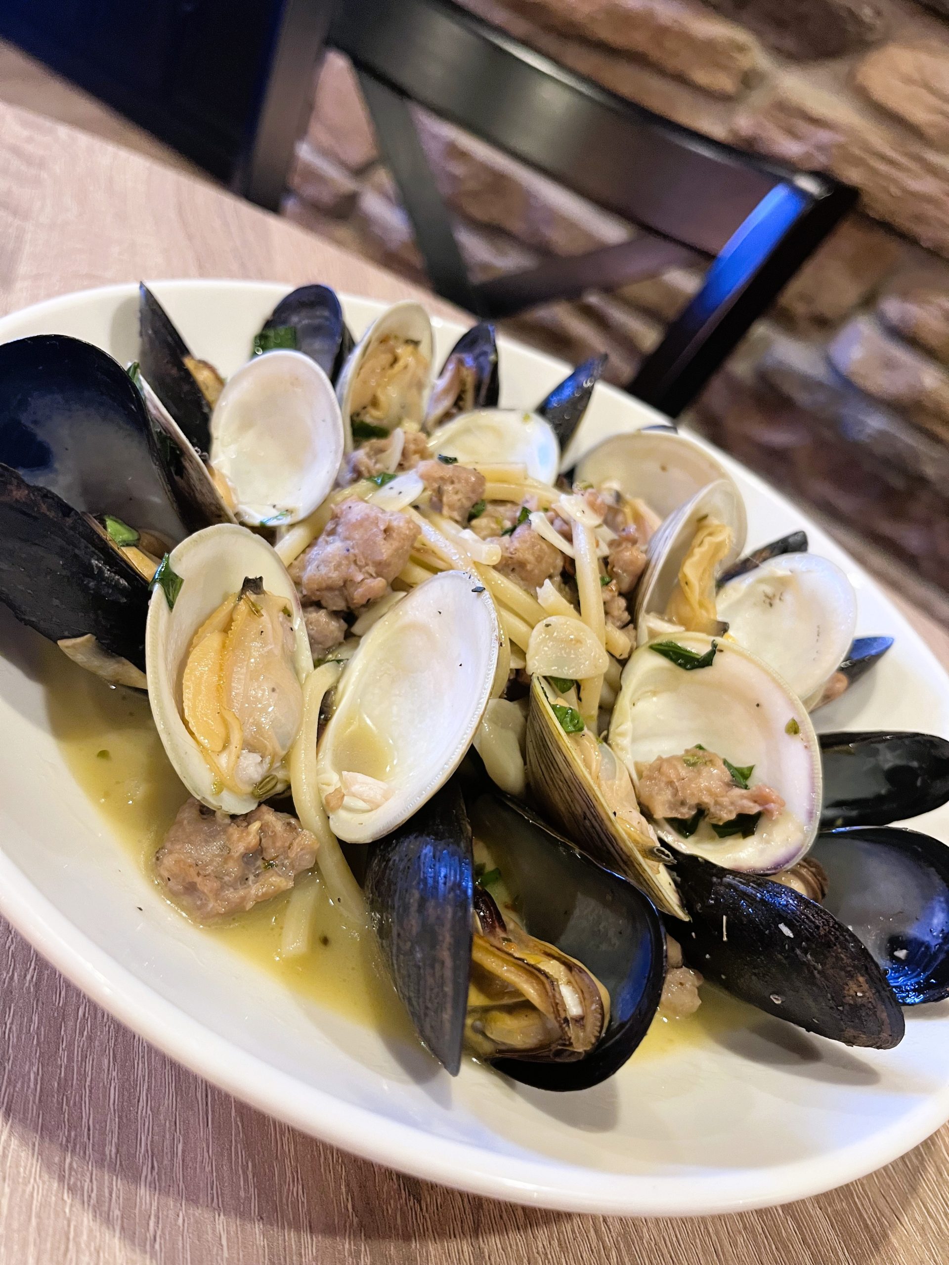 A plate of mixed seafood including mussels and clams, garnished with herbs, served on a wooden table.